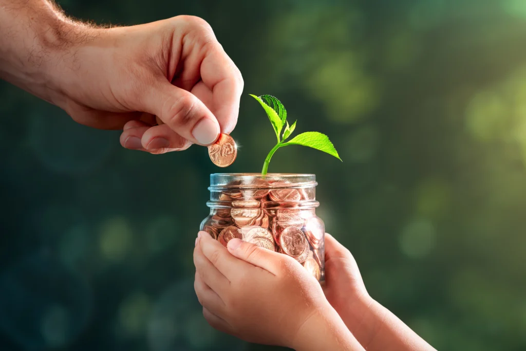 A hand taking a penny out of a child's jar with a plant in it, a visual representation of estate tax and gift tax.